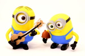 Zwei Minions - einer mit Gitarre und ein anderer, der gespannt zuhört.